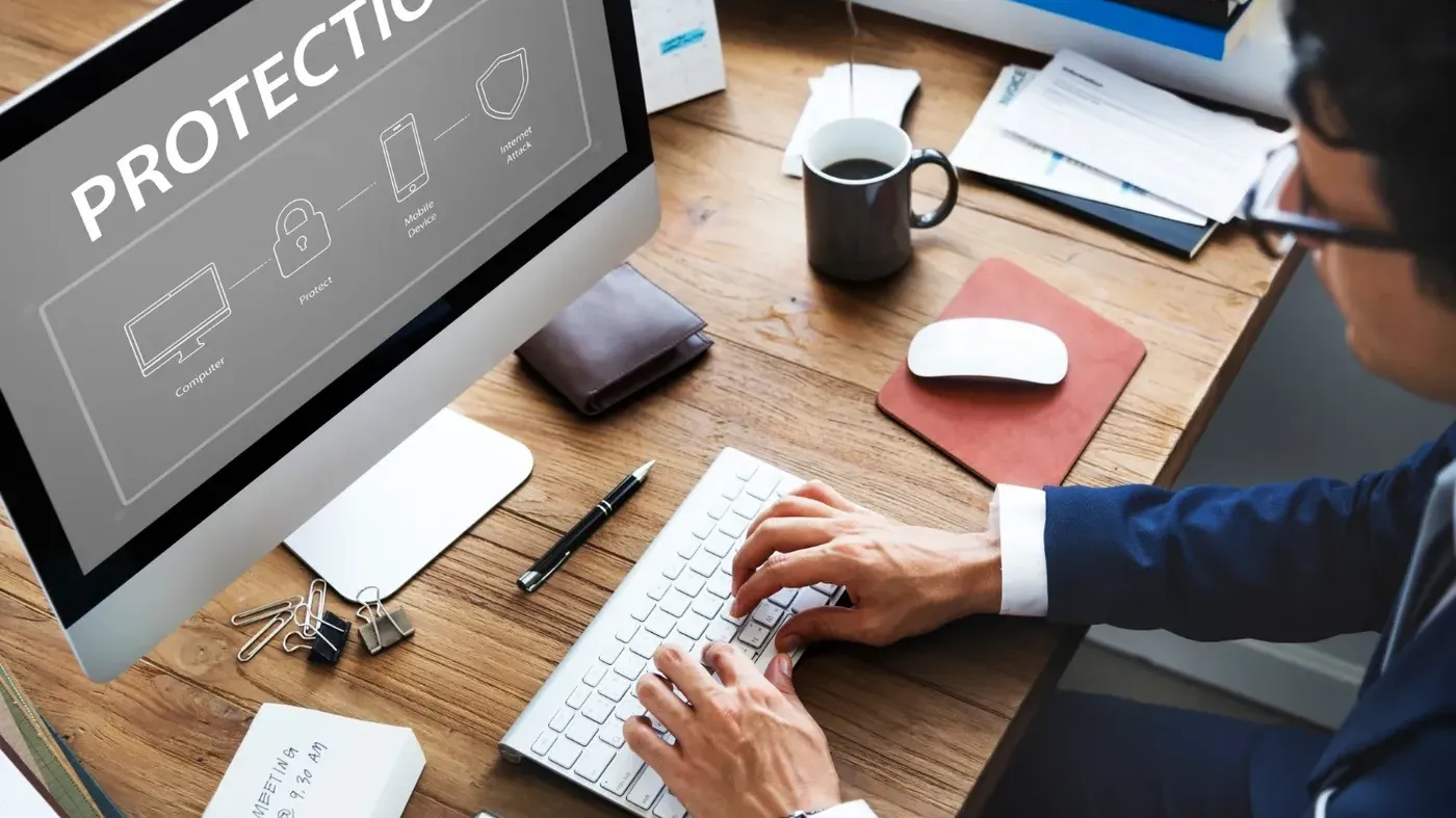 A professional using a desk top in an office with the word protection over it