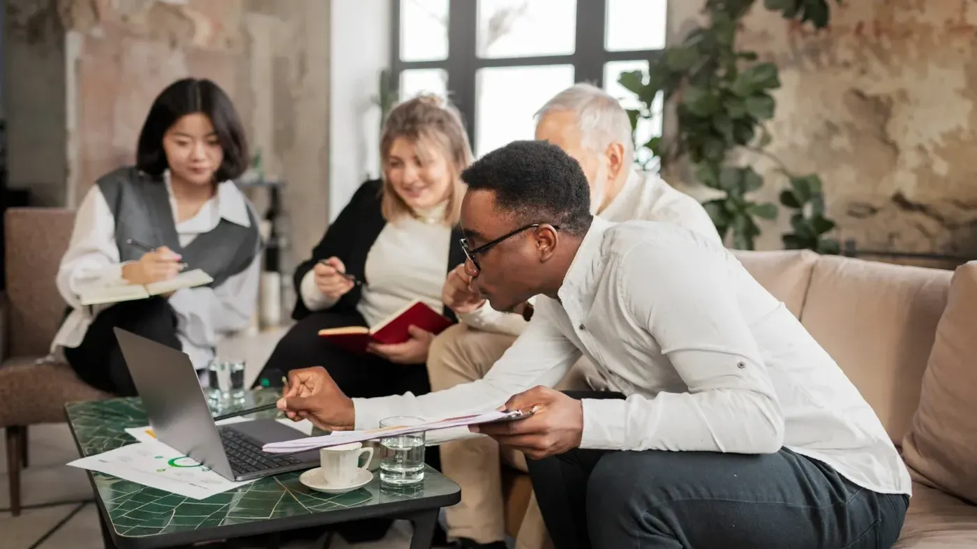 Business professionals sit together in a casual setting reviewing polices
