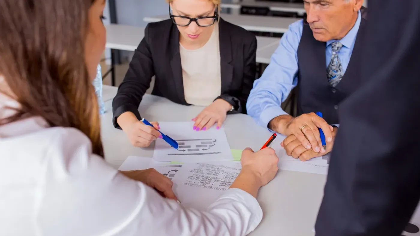Two women holding pens and a man looking at a sheet together