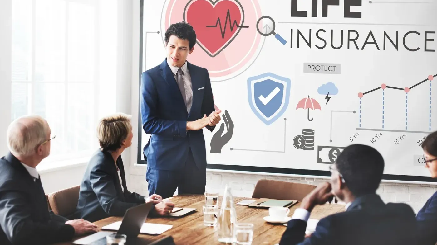 A group of people in a meeting with a man presenting the topic on life insurance