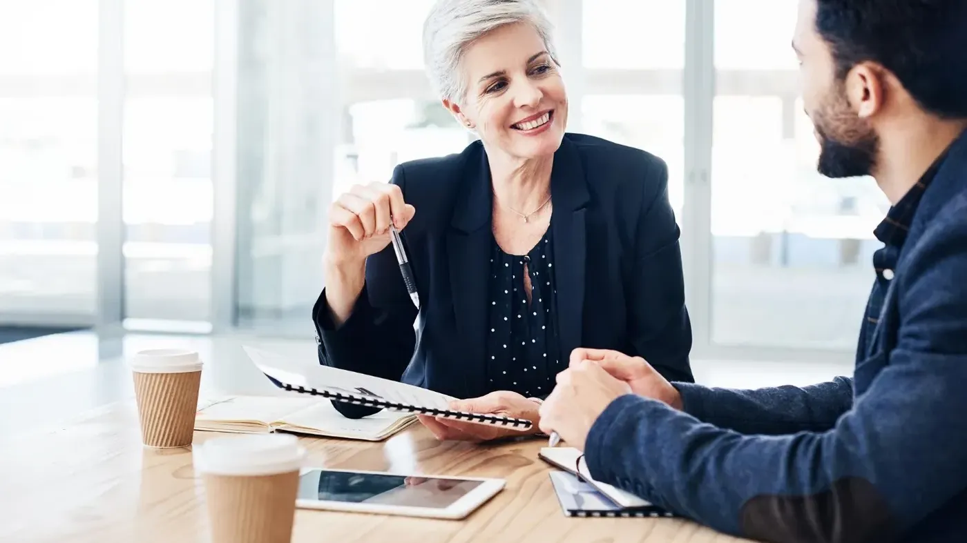 small business insurance broker represented by two business professionals reviewing papers and talking over coffee